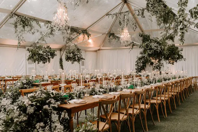 Tented reception with long wooden tables and hanging greenery at Villa Woodbine